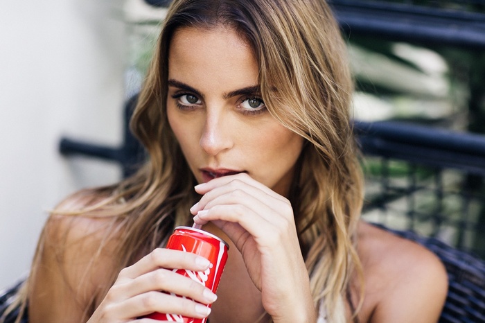 Woman drinking Coca-Cola from a can with a straw