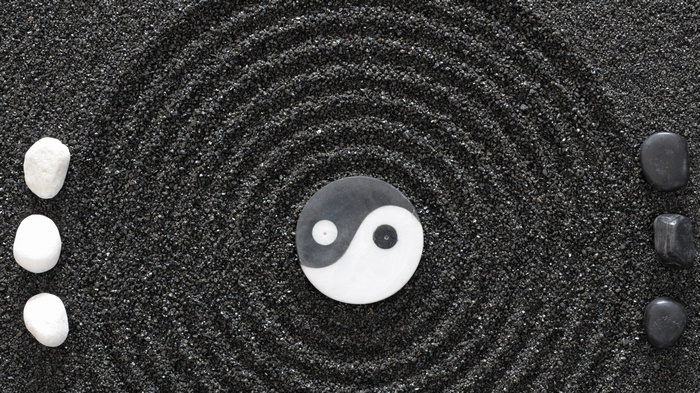 Yin and Yang symbol with stones on black sand