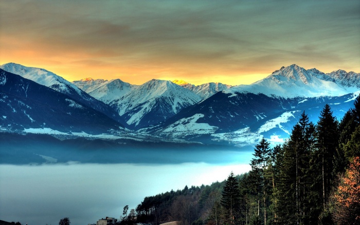 Snow-capped mountains over a foggy valley at sunrise
