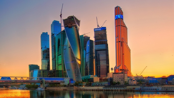 Moscow City skyscrapers at sunset with river and bridge