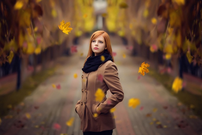 Woman with red hair in a brown coat in autumn
