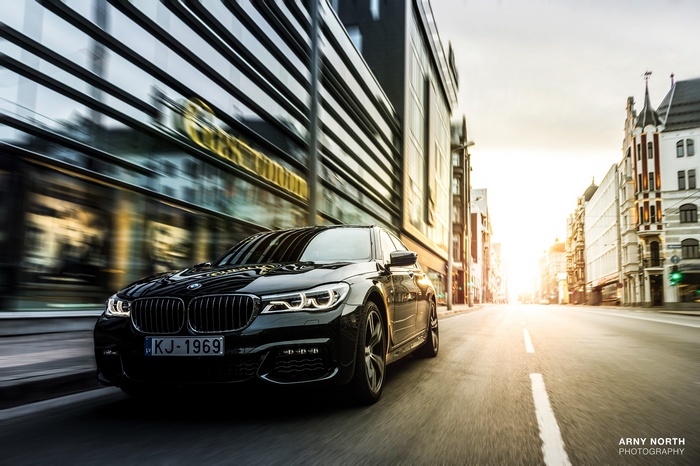 Black BMW driving down a street in Riga, Latvia