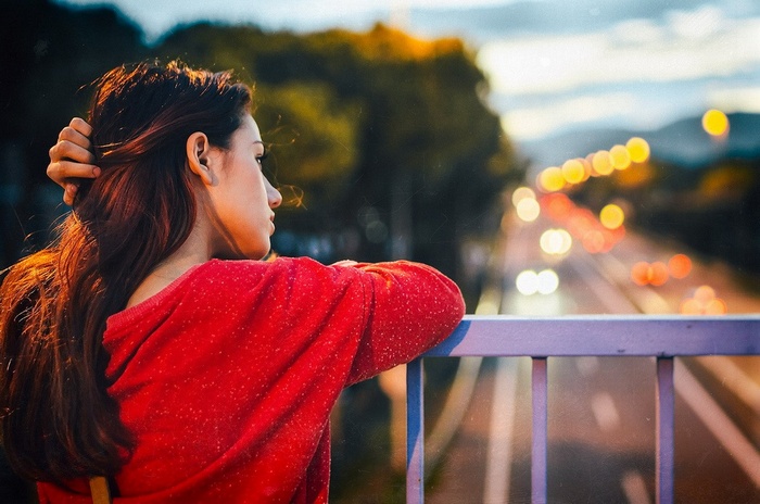 Woman in red sweater looking at city lights