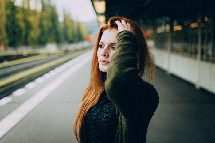 Redhead woman with hands in hair at train station