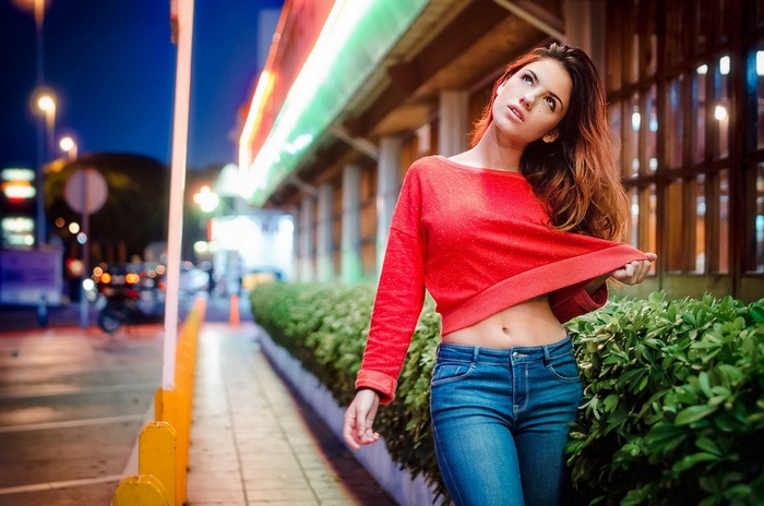 Woman in red crop top and jeans at night
