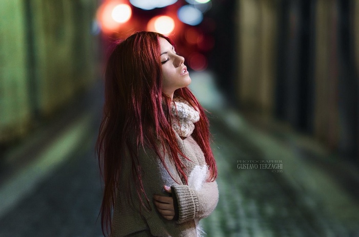Redhead woman with closed eyes in a street at night