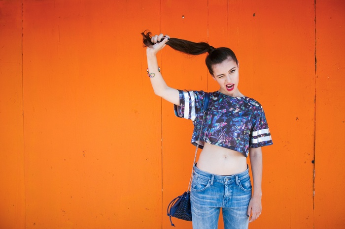 Woman in crop top and jeans holding her ponytail
