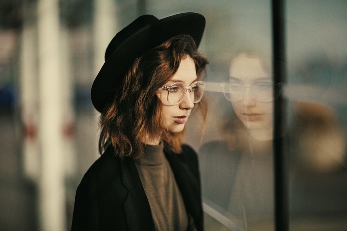 Jesse Herzog with hat and glasses looking out window