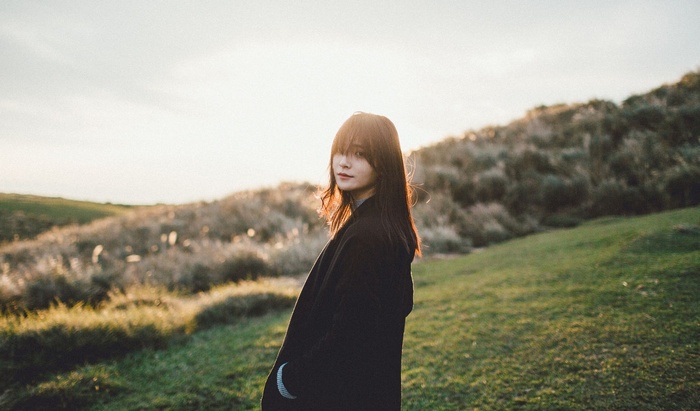 Asian woman with dark hair in a field at sunset
