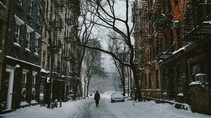 Person walking down a snowy street in a city