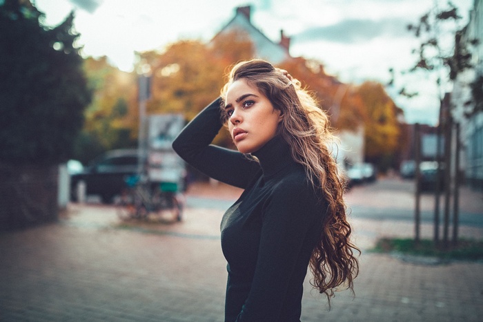Woman with long wavy brunette hair wearing a turtleneck outdoors