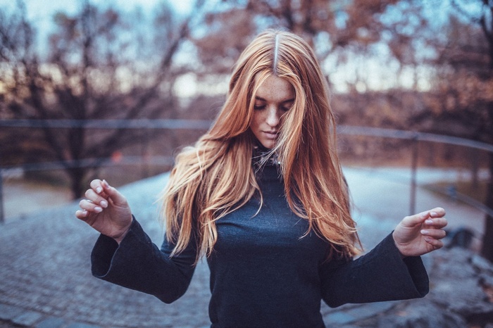 Redhead woman with hair in face outdoors