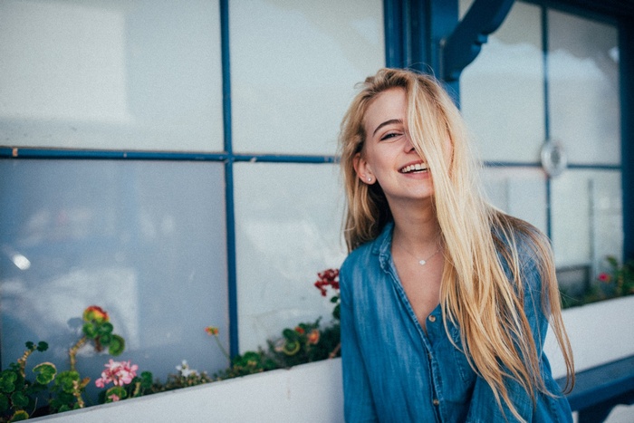 Woman with blonde hair in a denim shirt smiling