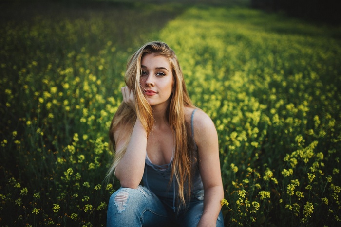 Woman in jeans sitting in a field of yellow flowers