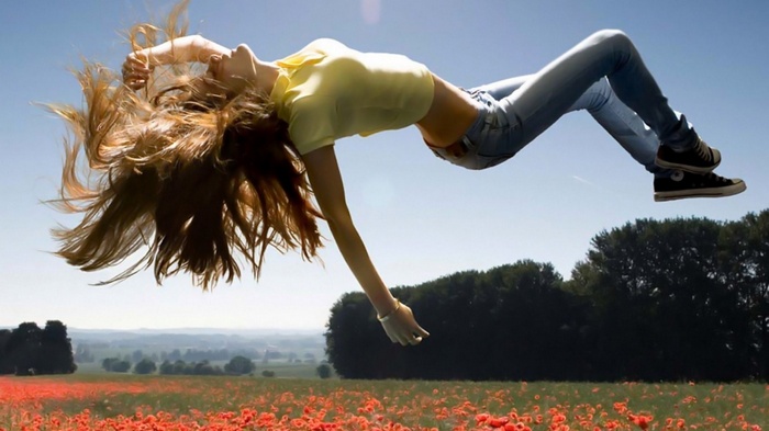 Woman floating over a field of poppies