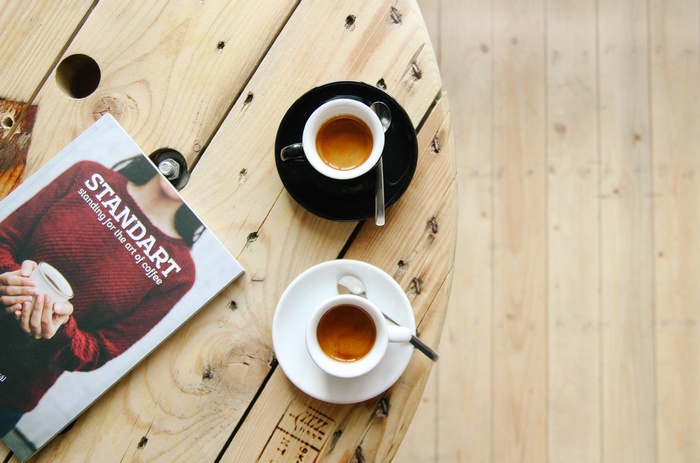 Two cups of coffee and a magazine on a wooden table