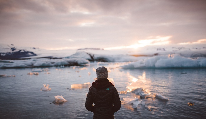 Woman in jacket and bonnet by icy water