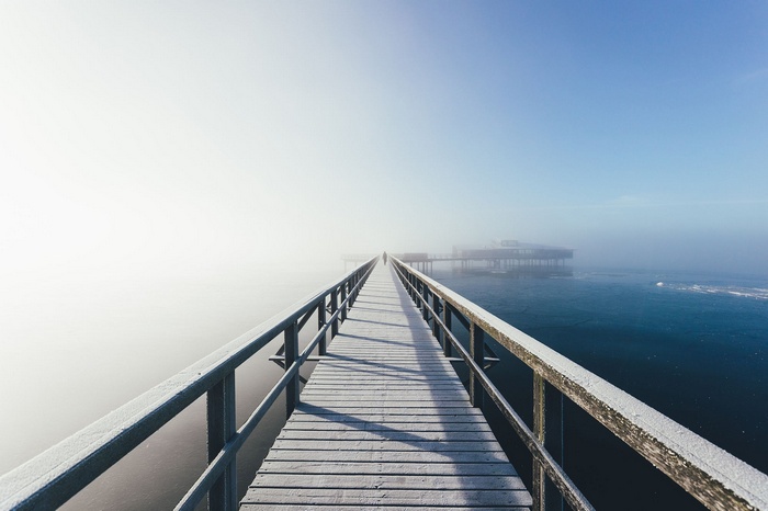 Wooden bridge over the sea in mist