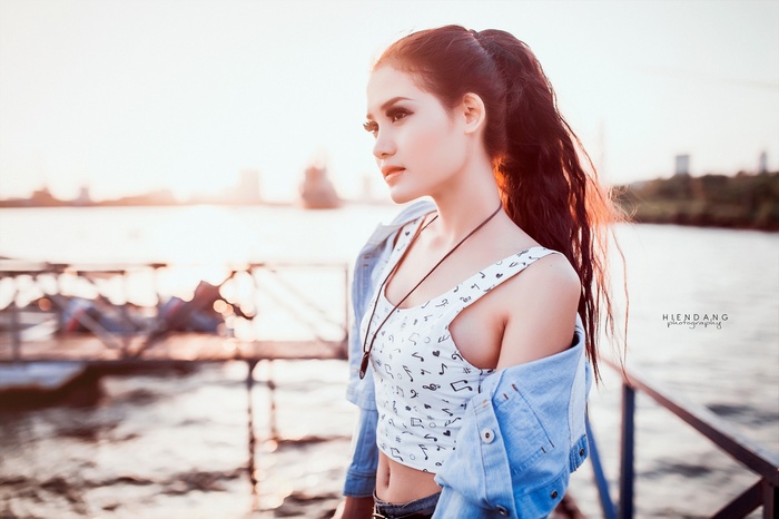 Asian woman with ponytail wearing a crop top and denim jacket