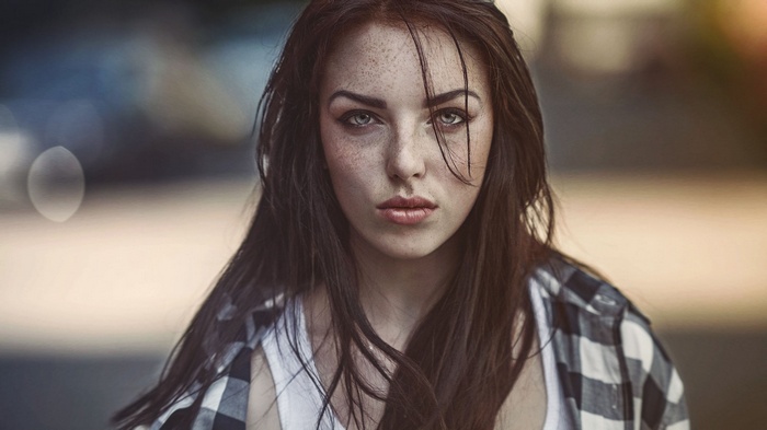 Woman with freckles and blue eyes wearing a plaid shirt