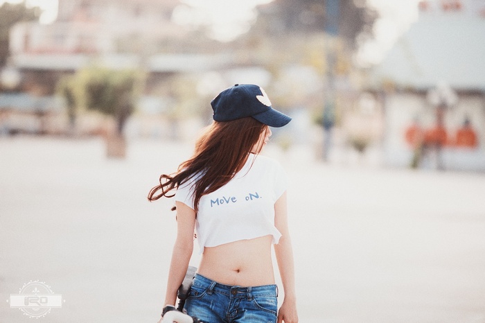 Woman wearing a crop top and jeans with a skateboard