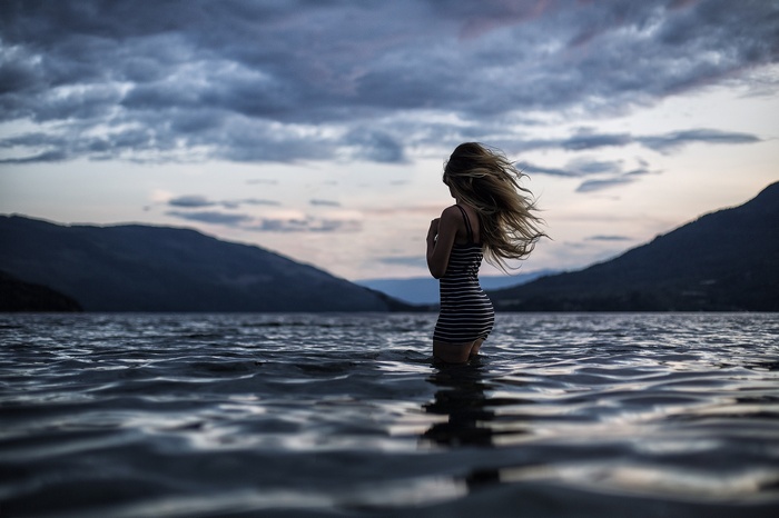 Woman in striped dress standing in water at dusk