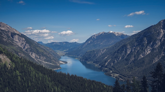 Mountain lake surrounded by forested slopes and snow-capped peaks
