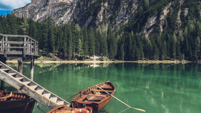 Wooden boats on a clear lake with mountains and trees