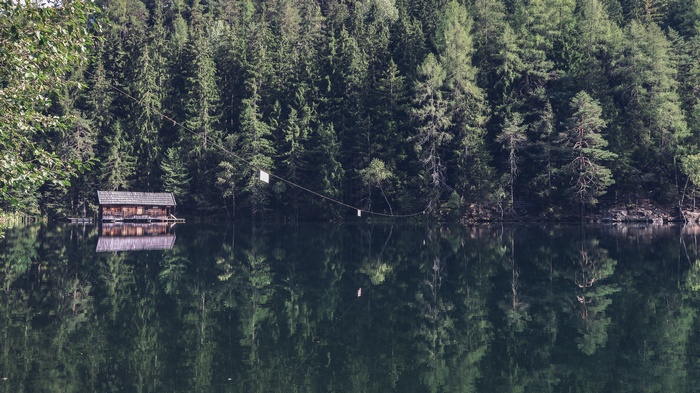 Wooden cabin on a lake with forest reflection