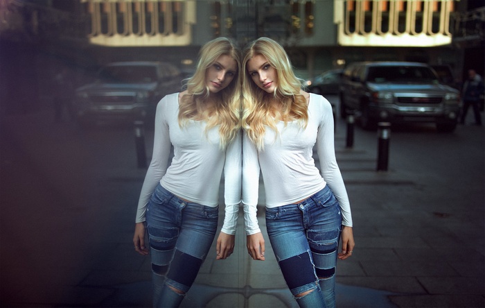 Woman in white shirt and jeans reflected in glass