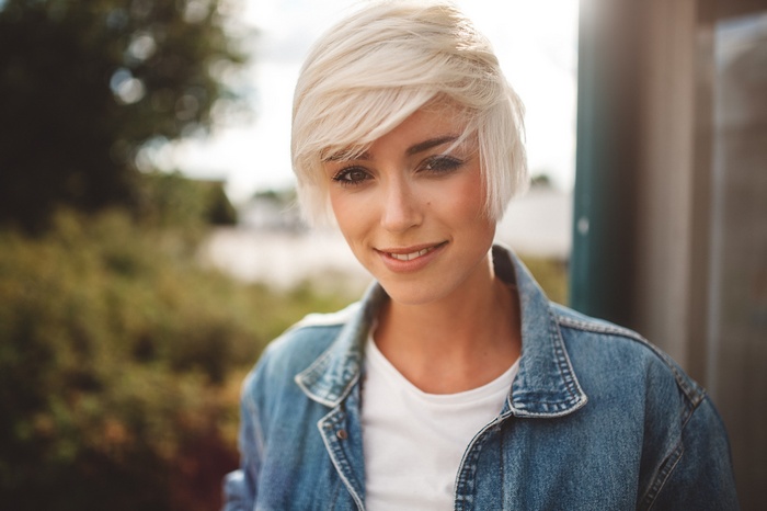 Woman with short blonde hair wearing denim jacket