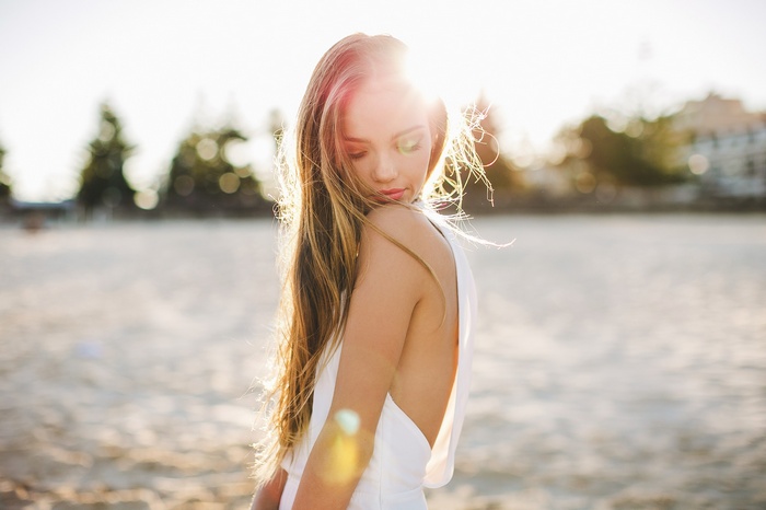 Woman in white dress on a beach at sunset