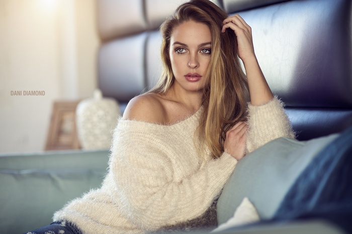 Dani Diamond in a white sweater on a couch