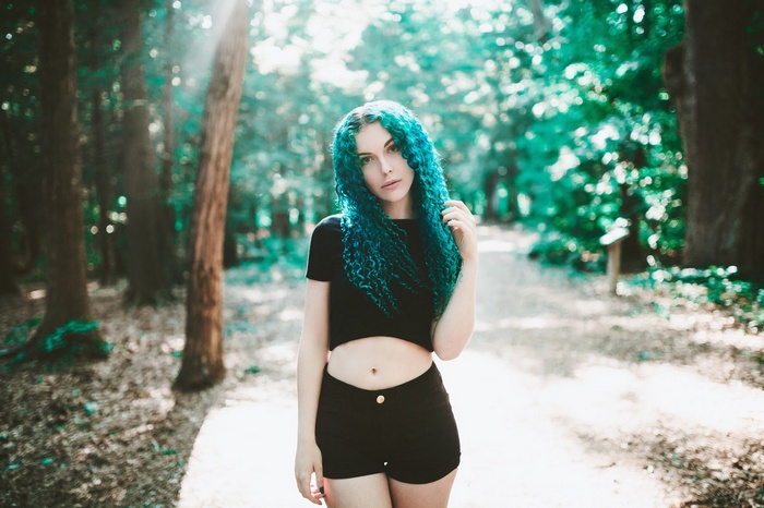 Woman with blue curly hair in a forest