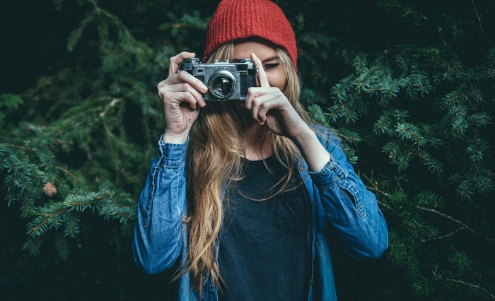 Woman in red beanie taking a photo with a vintage camera