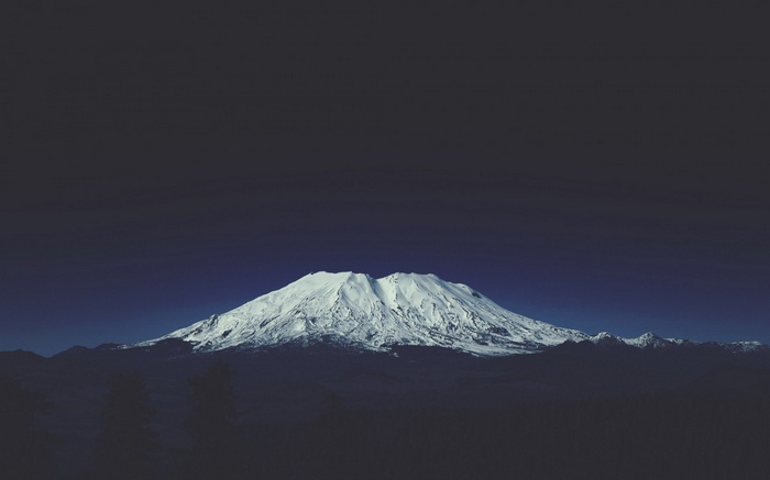 Snow-capped mountain under a dark blue sky