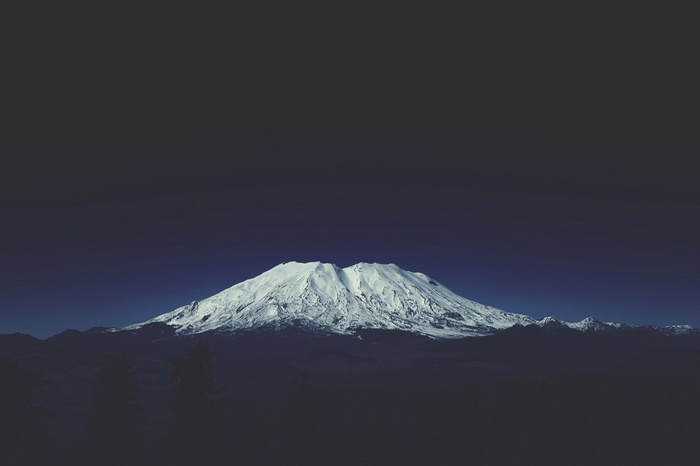 Snow-covered mountain range under a dark sky