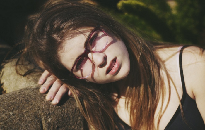 Woman with glasses leaning on a rock