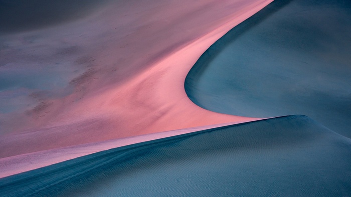 Pink and blue sand dunes in a desert landscape