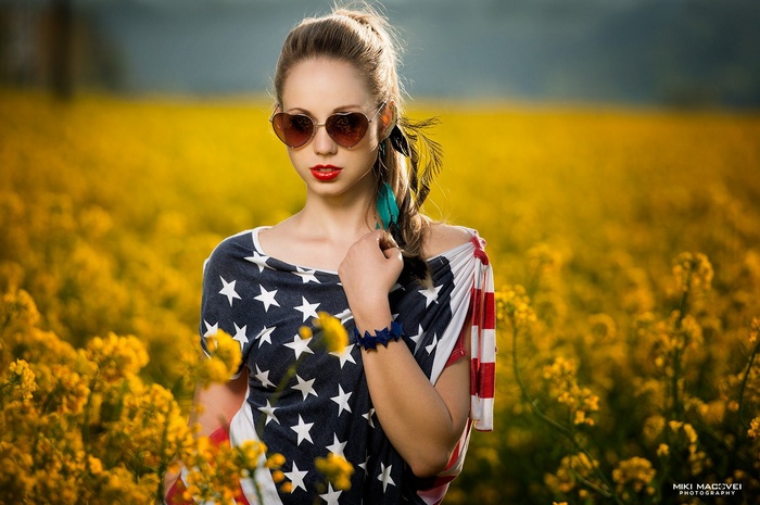 Woman in USA flag shirt and heart sunglasses in field