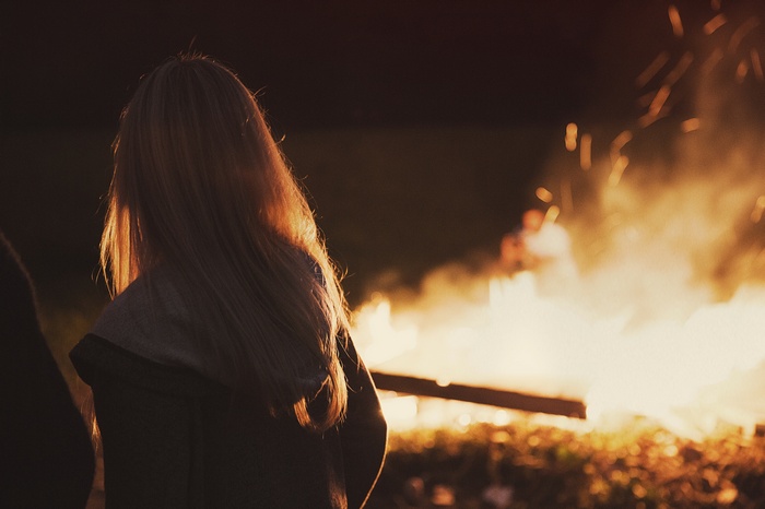 Woman with blonde hair by a campfire