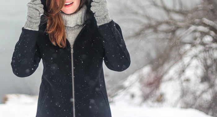 Woman in winter coat and mittens in snow