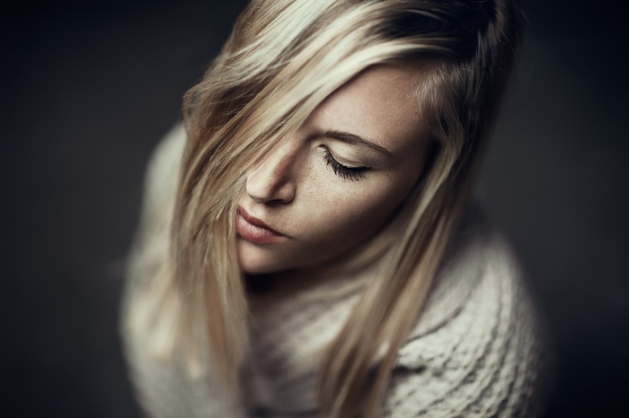 Woman with blonde hair and freckles wearing a sweater