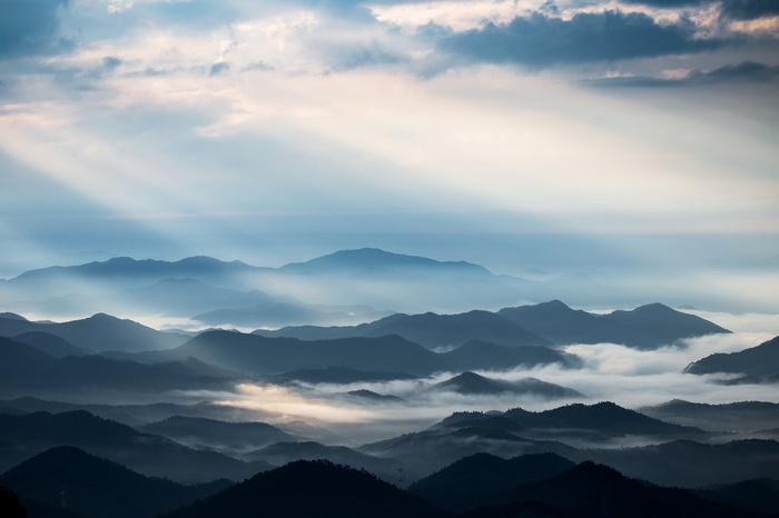 Sun rays over misty mountains and clouds