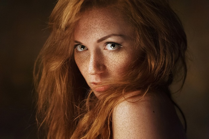 Woman with red hair and freckles looking at viewer
