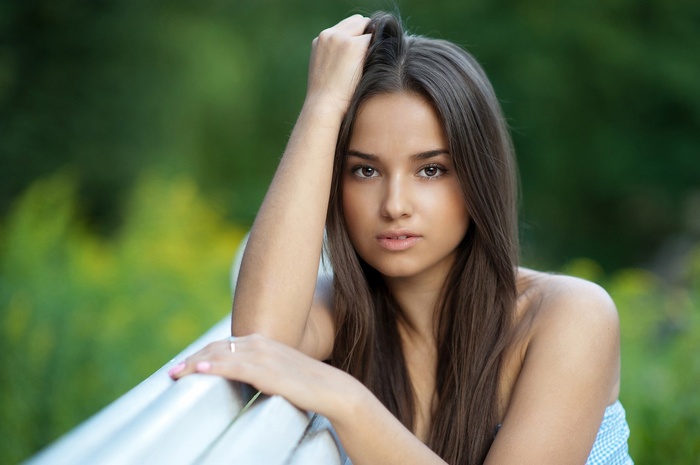 Woman with hand in hair sitting outdoors