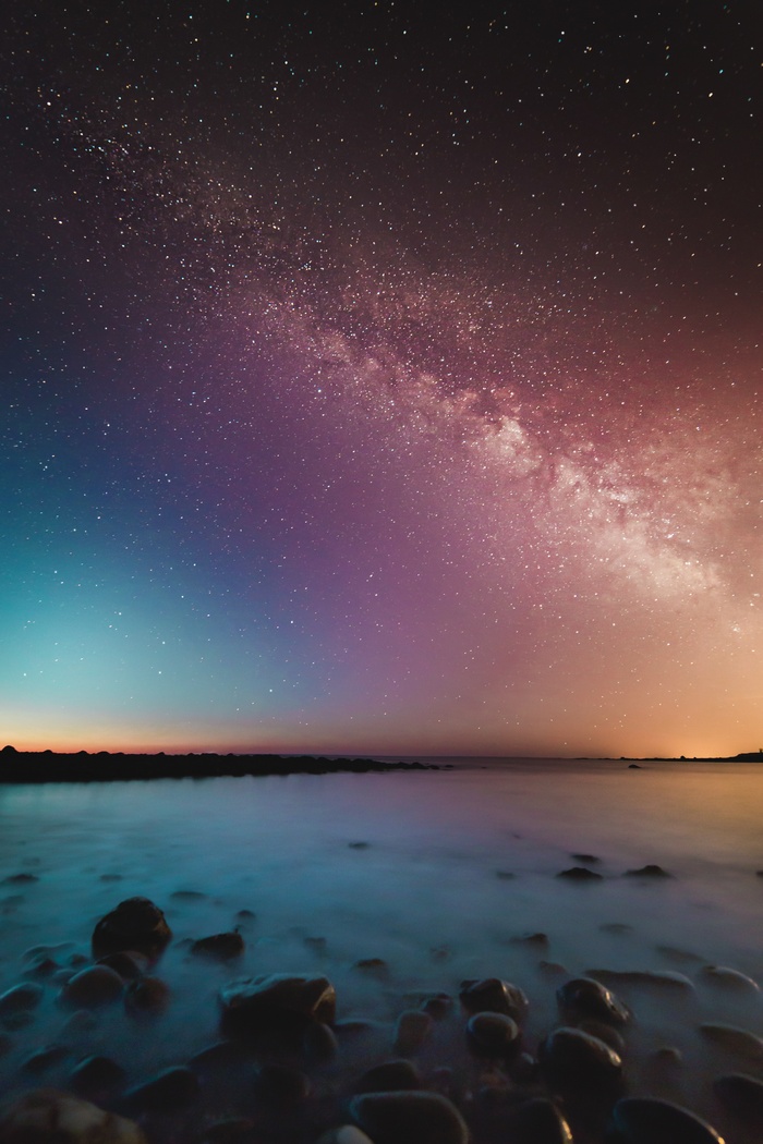 Milky Way galaxy over a rocky shore at night