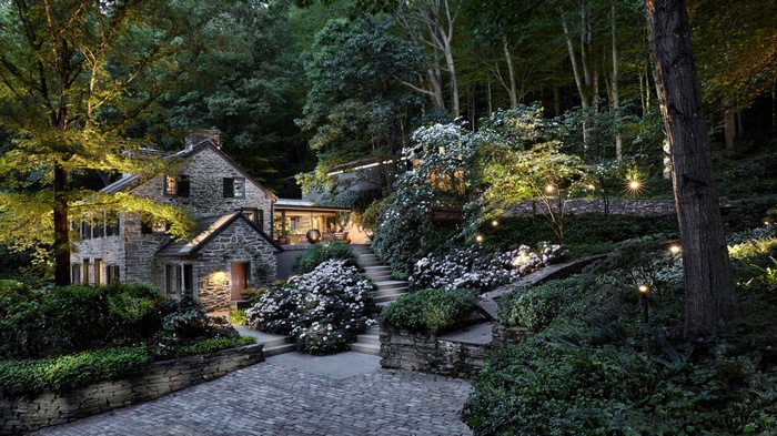 Stone cottage with garden stairs and lights in a forest