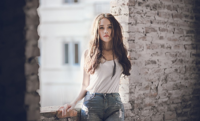 Woman in white tank top and ripped jeans