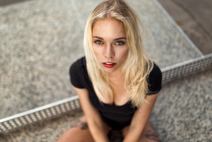Blonde woman with tattoos and blue eyes looking at viewer